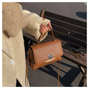 Detail of brown PU leather handbag featuring vertical texture and silver metal swivel lock
