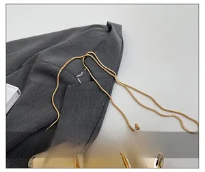 Close-up of polished gold snake chain strap on luxury metallic evening clutch bag