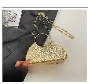 Detailed view of golden metallic evening bag featuring hammer texture and ring handle