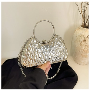 Detail of silver evening bag with hammered metal texture, ring handle and sphere clasp