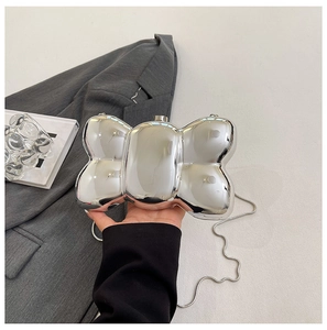 Macro view of mirror silver bow-shaped hard shell clutch bag with delicate chain strap