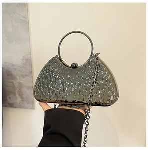 Close-up of a silver metallic evening bag with wavy texture and circular handle detail