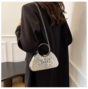 Detail of silver metallic evening bag featuring ripple texture and circular handle