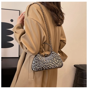 Detail of silver metallic evening bag with hammered texture and round metal handle on model