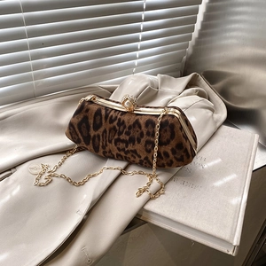 Leopard print chain bag with pearl clasp placed on beige blazer in soft natural light