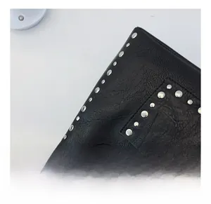 Close-up of black leather material with silver metal rivets and fine stitching details