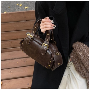 Close-up of vintage dark brown faux leather shell bag with gold hardware and metal rivets