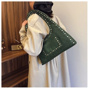 Detail of dark green rivet shoulder bag worn by model in a vintage interior setting