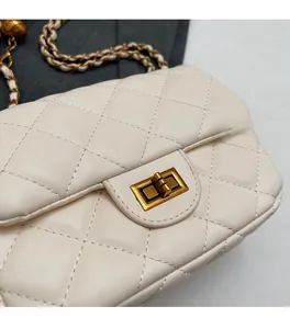 Close-up of cream quilted leather flap bag with gold clasp and chain strap detail