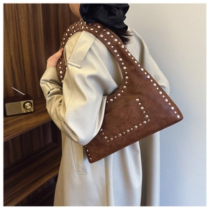 Detail of vintage brown shoulder bag with silver rivets and textured synthetic leather