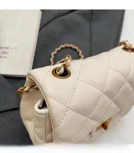 Detail of cream quilted leather bag with matte gold chain and diamond stitching