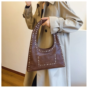 Detail of vintage brown leather hobo bag with silver rivet studs and textured finish