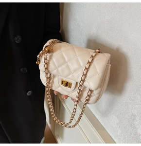 Detail of beige quilted leather crossbody bag with gold chain and metal ball charm