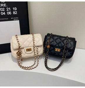 Detail of quilted leather bags in white and black with gold hardware and chain straps