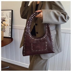 Detail of burgundy PU leather shoulder bag featuring silver metal rivets and vintage style
