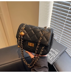 Detail of black quilted leather crossbody bag featuring adjustable gold ball chain buckle