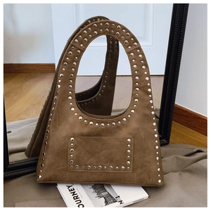 Detail of vintage brown tote bag featuring metallic rivets and textured faux leather