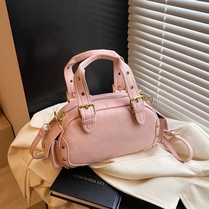 Pink retro shell handbag with gold hardware and rivets on a white fabric surface