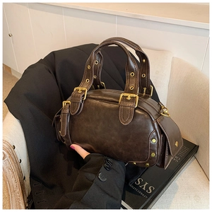 Vintage brown leather shell handbag with gold buckle on a retro beige armchair