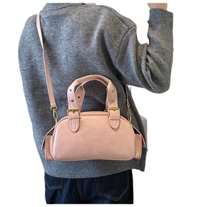 Pink retro shell-shaped top handle bag with crossbody strap shown on a model