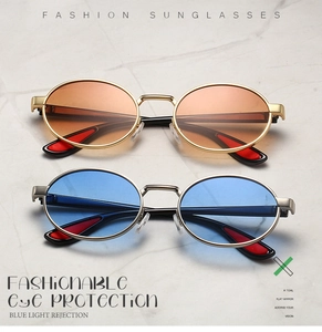 Detail of retro oval metal sunglasses with blue and amber lenses on marble background