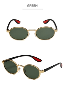 Detail view of oval metal sunglasses featuring gold frames and green lenses with red accents