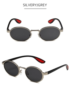 Detail of silvery metal oval frame sunglasses with black lenses and red temple accents