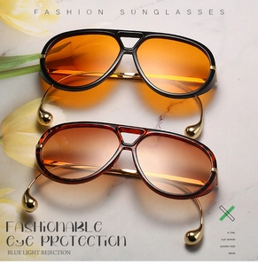 Detalle de gafas de sol de gran tamaño con colgantes dorados de lágrima en las patillas