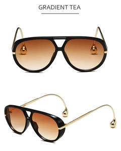 Detalle de gafas de sol aviador con lentes degradadas té y patillas de metal dorado