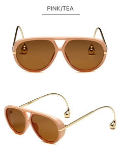 Detalle de gafas de sol aviador rosas con lentes té y patillas doradas con colgante