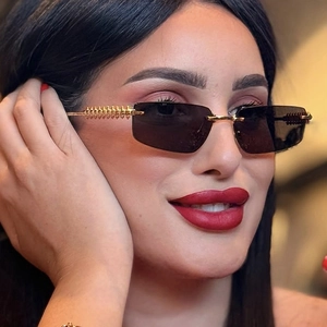 Close-up of rimless rectangle sunglasses with gold spiral metal temples and dark lenses