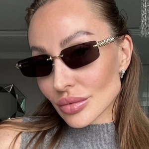 Detail of rimless rectangle sunglasses with brown lenses and gold twisted metal temples