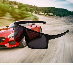 Detail of sleek black wrap-around cycling sunglasses over a high-speed racing car background