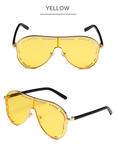 Detail of yellow one-piece oversized sunglasses with gold metal frame and black temples