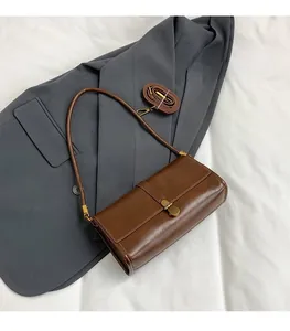Detail of dark brown leather handbag featuring golden lock and detachable long shoulder strap