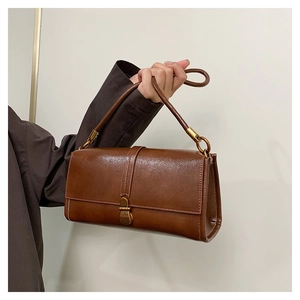 Detail of vintage brown leather handbag featuring a sleek rectangle shape and gold buckle