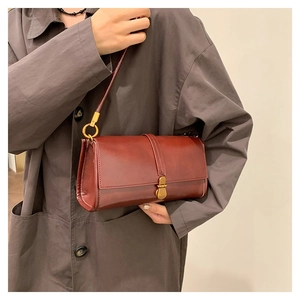 Detail of vintage reddish-brown leather handbag with elegant gold metal buckle closure
