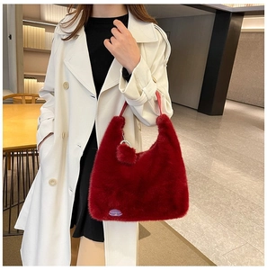 Detail of red plush faux rabbit fur hobo bag featuring a fuzzy ball charm and brand label