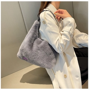 Close-up of grey plush faux fur shoulder bag with purple fashion label on a model
