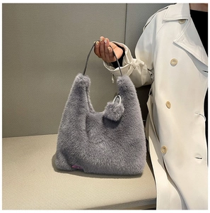 Detailed view of grey faux fur hobo bag with black handle and purple fashion label