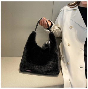 Detail of black faux fur handbag with fluffy texture and purple label on a grey background