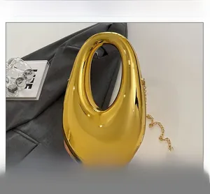 Detail view of a metallic gold oval evening clutch with chain strap on a blazer background