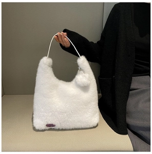 Close-up of white faux fur shoulder bag featuring a fashion tag and rhinestone charm detail