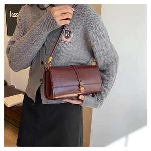 Detail view of burgundy leather flap bag with antique bronze buckle and slim shoulder strap