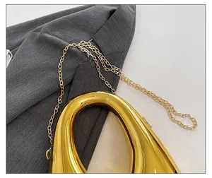 Detailed close-up of golden mirrored hollow water drop bag with delicate chain strap