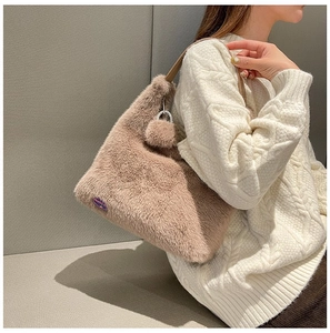 Close-up of Mocha brown plush shoulder bag with purple label and soft fluffy ball charm