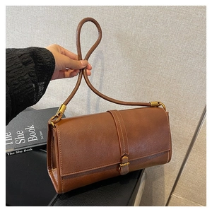 Close-up of vintage brown leather handbag featuring a sleek metal buckle and fine texture