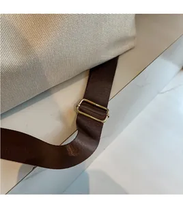 Detail of adjustable nylon shoulder strap with golden buckle on canvas crossbody bag
