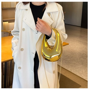 Close-up of a gold mirrored acrylic clutch bag with a sleek, minimalist curved design