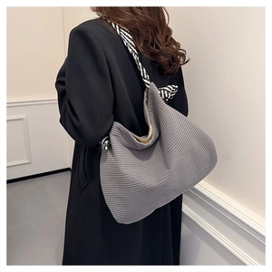 Dettaglio della borsa hobo in velluto a coste grigio con tracolla intrecciata a righe bianche